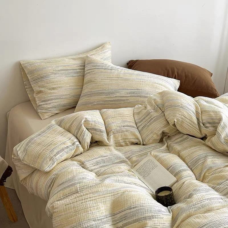 A cozy bed styled with a textured cream and beige striped bedding set, including a duvet cover and matching pillowcases, with a solid brown accent pillow in the background.