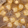 String lights shaped like seashells on a wooden surface with a candle and starfish.