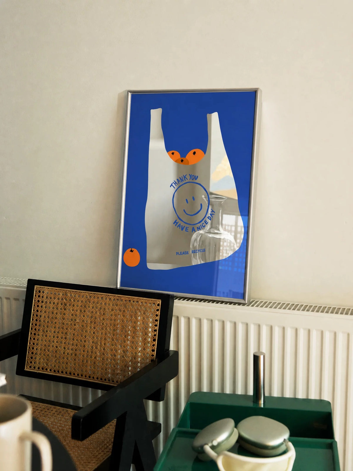 The Orange Bag mirror leans upright, with a white bag and orange fruit against a blue rectangular printed area.