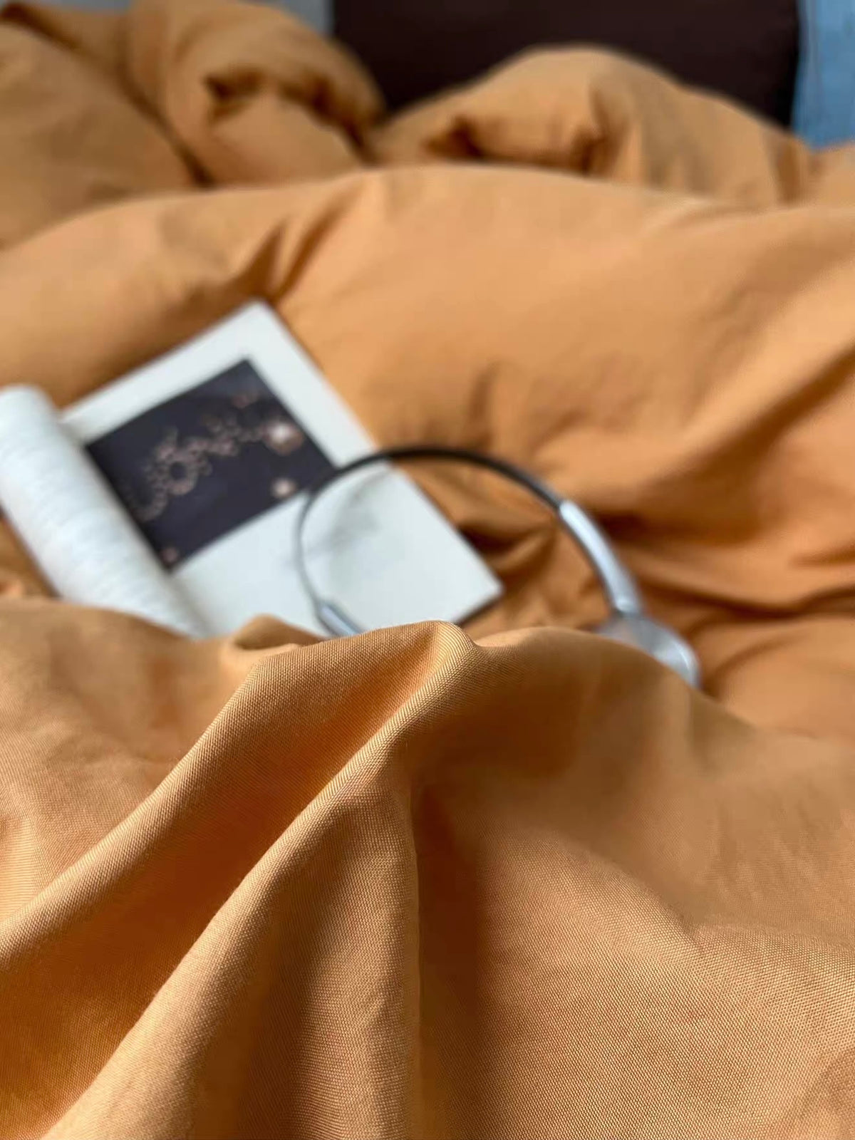 Orange duvet cover with a book and headphones resting on top