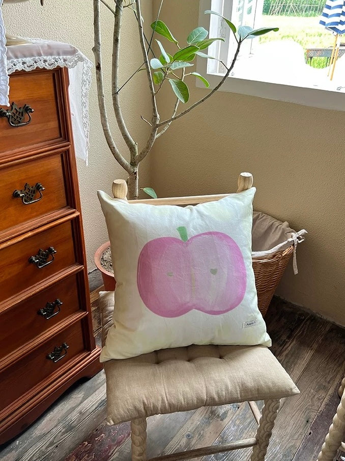 Painted pink apple throw pillow with small green hearts on a cream canvas cover