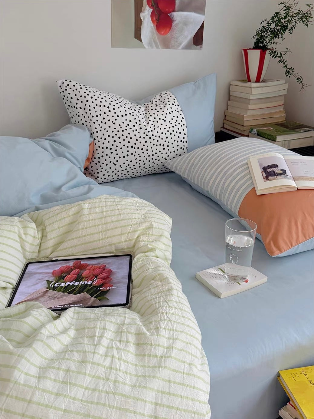 Pastel bedding shows a pale yellow textured grid beside a blue sheet, with a dotted pillow and an open book.