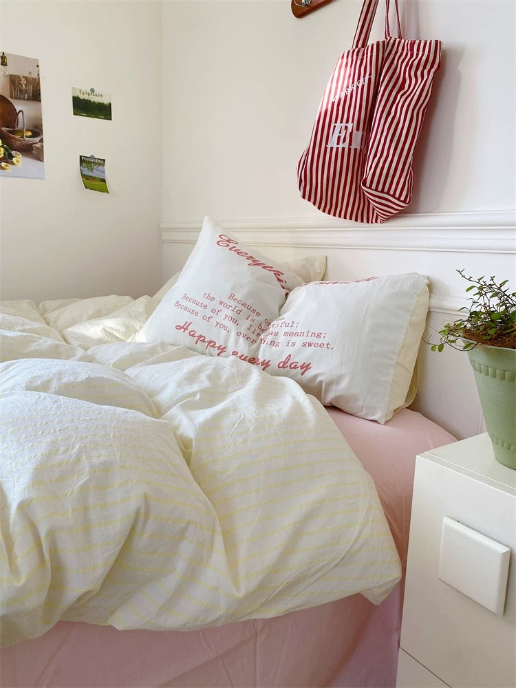 Bedroom with white bedding and pillows, red and white striped bag on headboard