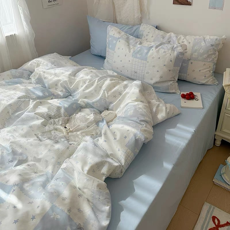 Cozy blue patchwork bedding with pillowcases on a white bed frame, perfect for aesthetic bedrooms.