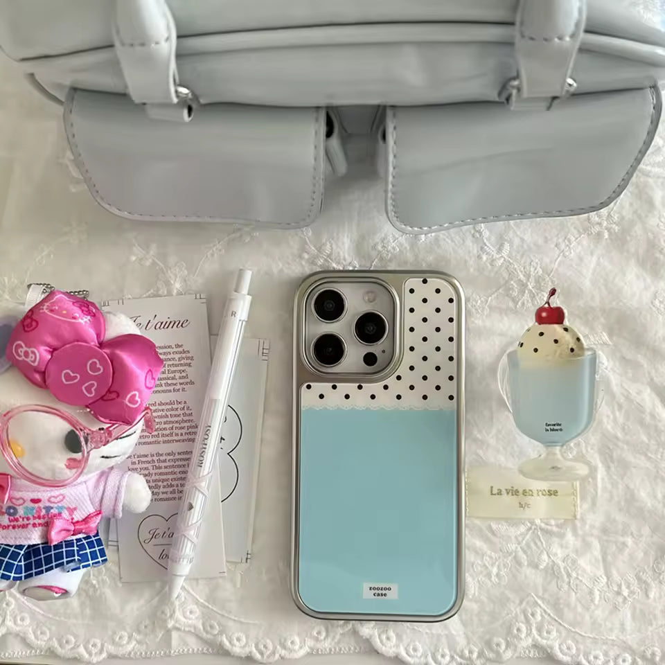 Phone case with polka dot design, small plush toy, and other items on a textured surface