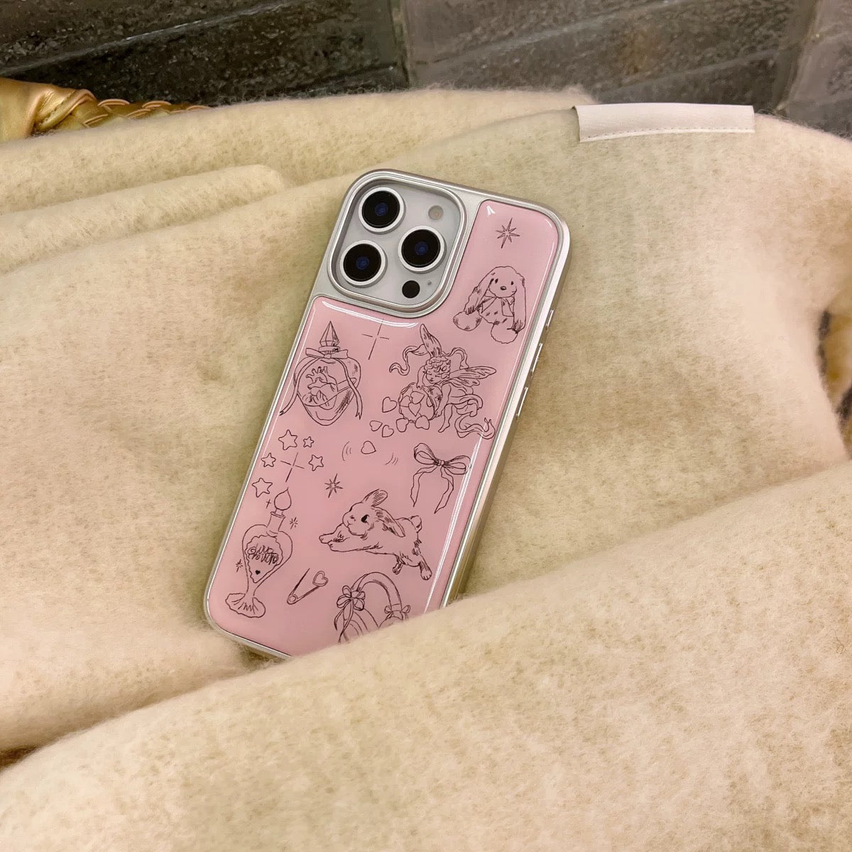 Pink phone case with black illustrations on a beige surface