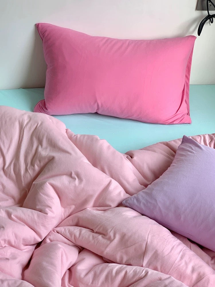 Pink bedding set on a bed with a light blue headboard.