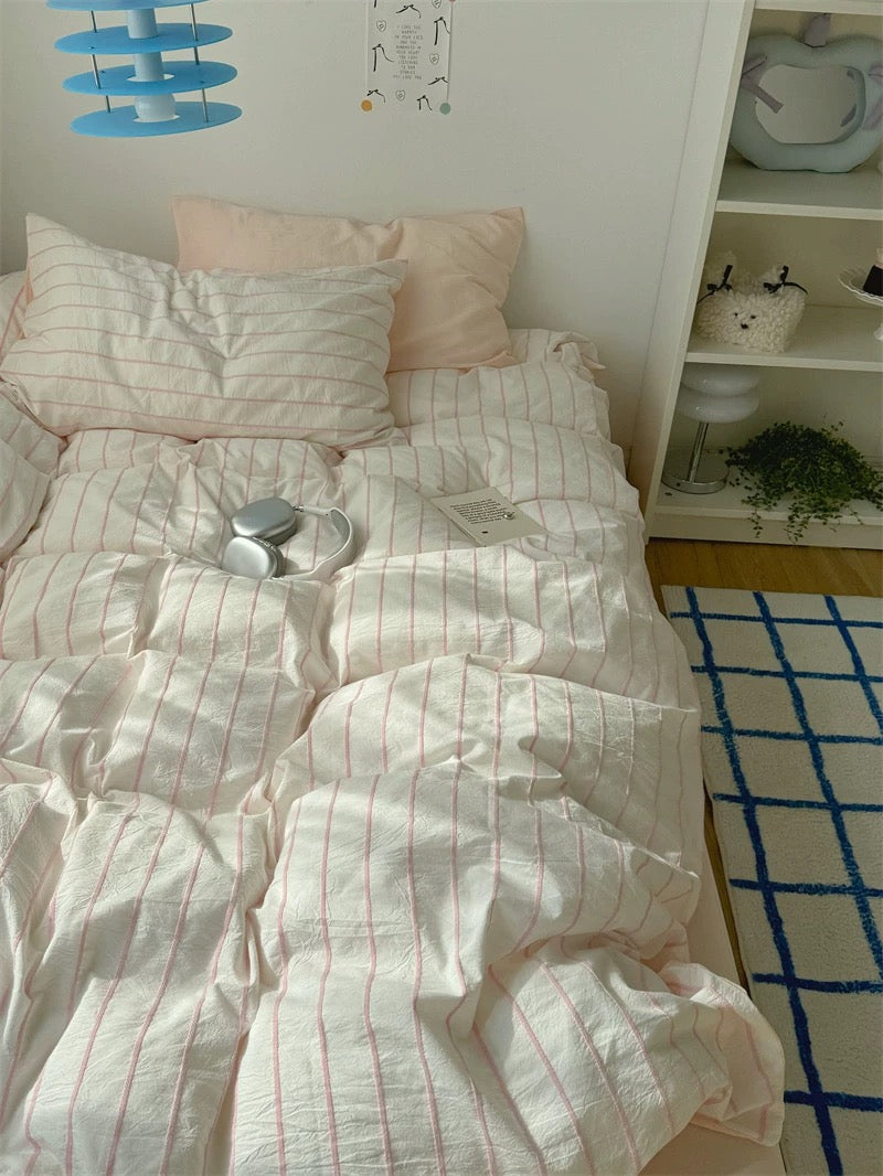 Bed with white and red striped bedding in a room with a shelf and decor.