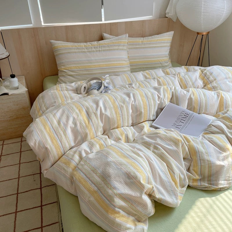 Bed with striped bedding and pillows in a bright room