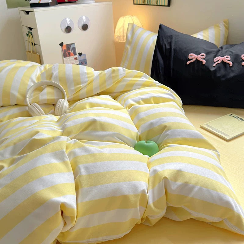 Comfortable and inviting bed setup with the yellow striped bedding set and cozy throw pillows.