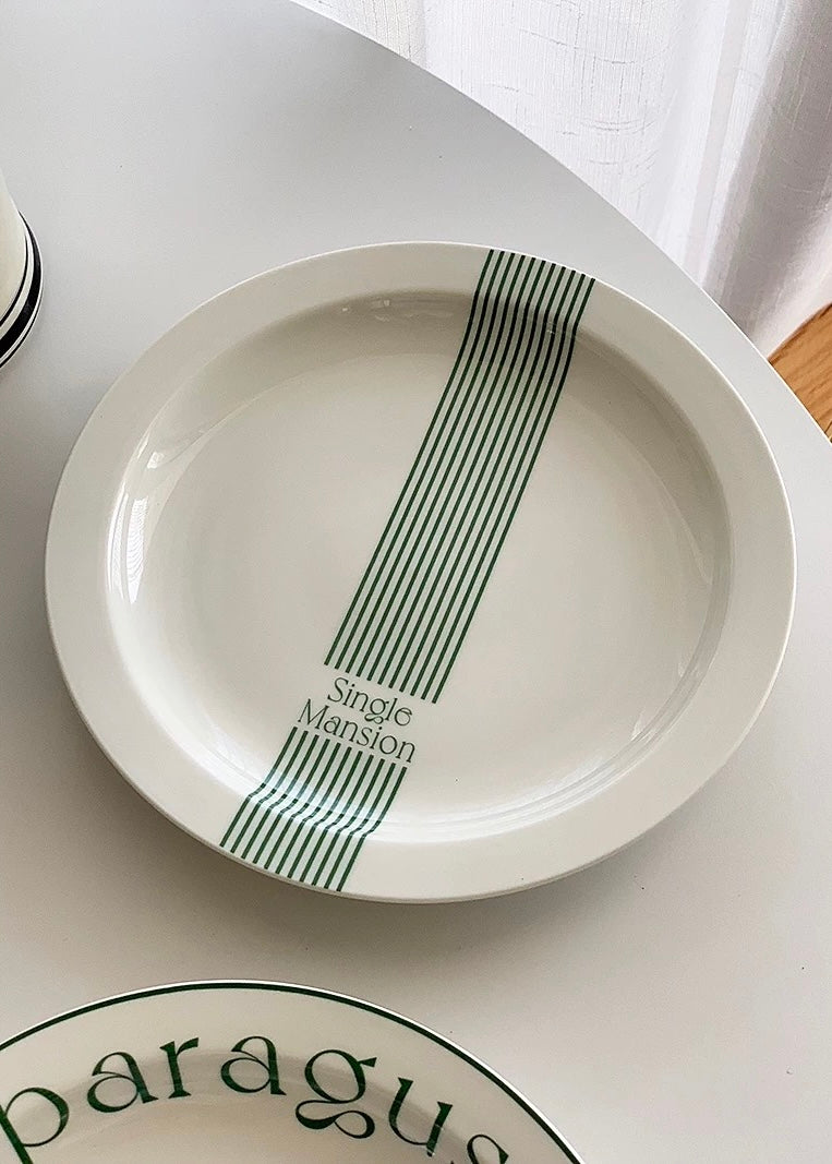 A white ceramic plate with a vertical green stripe pattern and the text 'Single Mansion' printed on it, shown on a white tabletop.