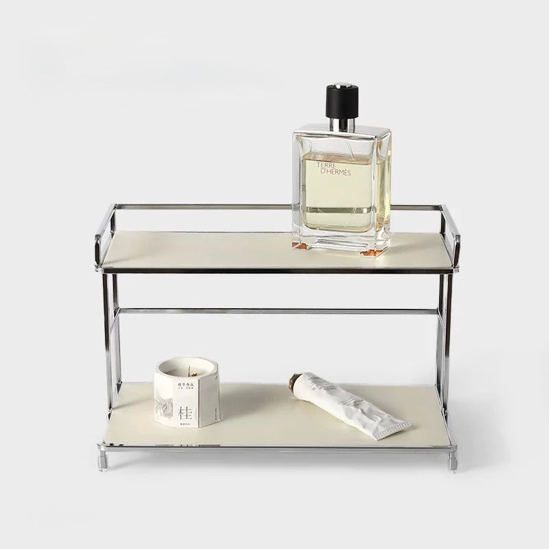 Small metal shelf with a glass container, candle, and tube of cream on a white background