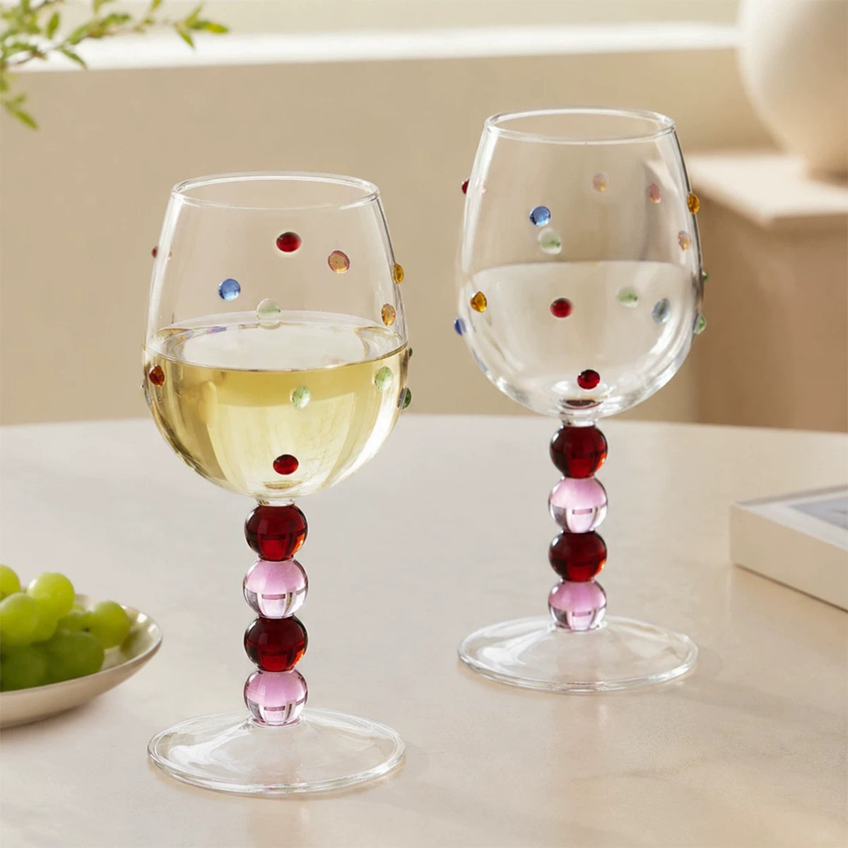 Pink chunky stem wine glasses with colorful raised dots styled on a table