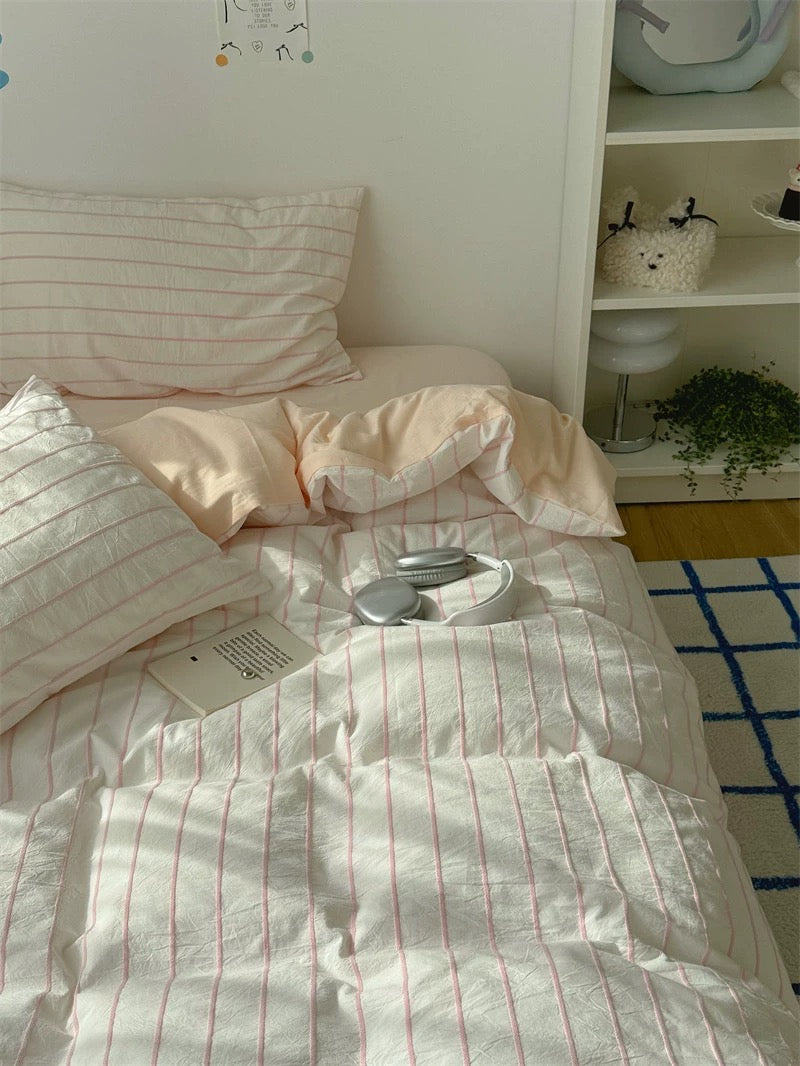 Bed with striped bedding and pillows in a room with a shelf and rug.