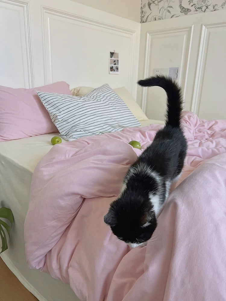 Pink cotton jersey duvet cover on a bed with a black and white cat