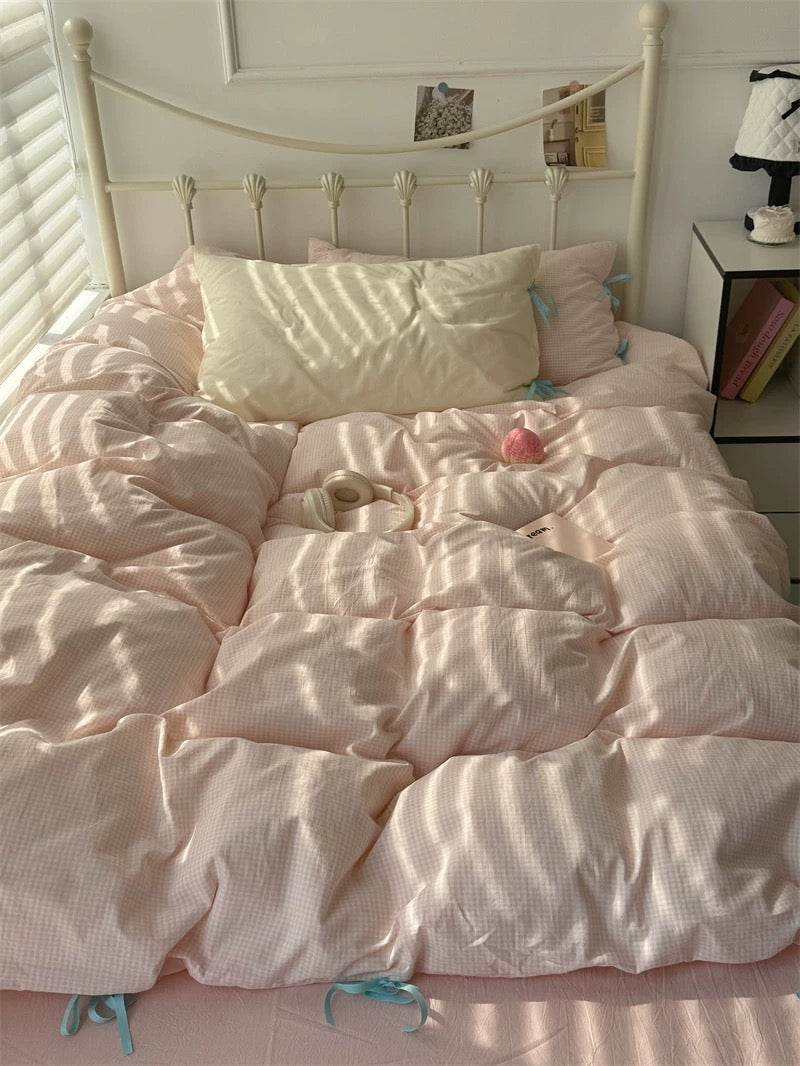 Pink comforter on a bed in a bedroom with a nightstand and decor items.