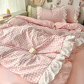 Pink gingham duvet with lace trim on a pastel pink bed