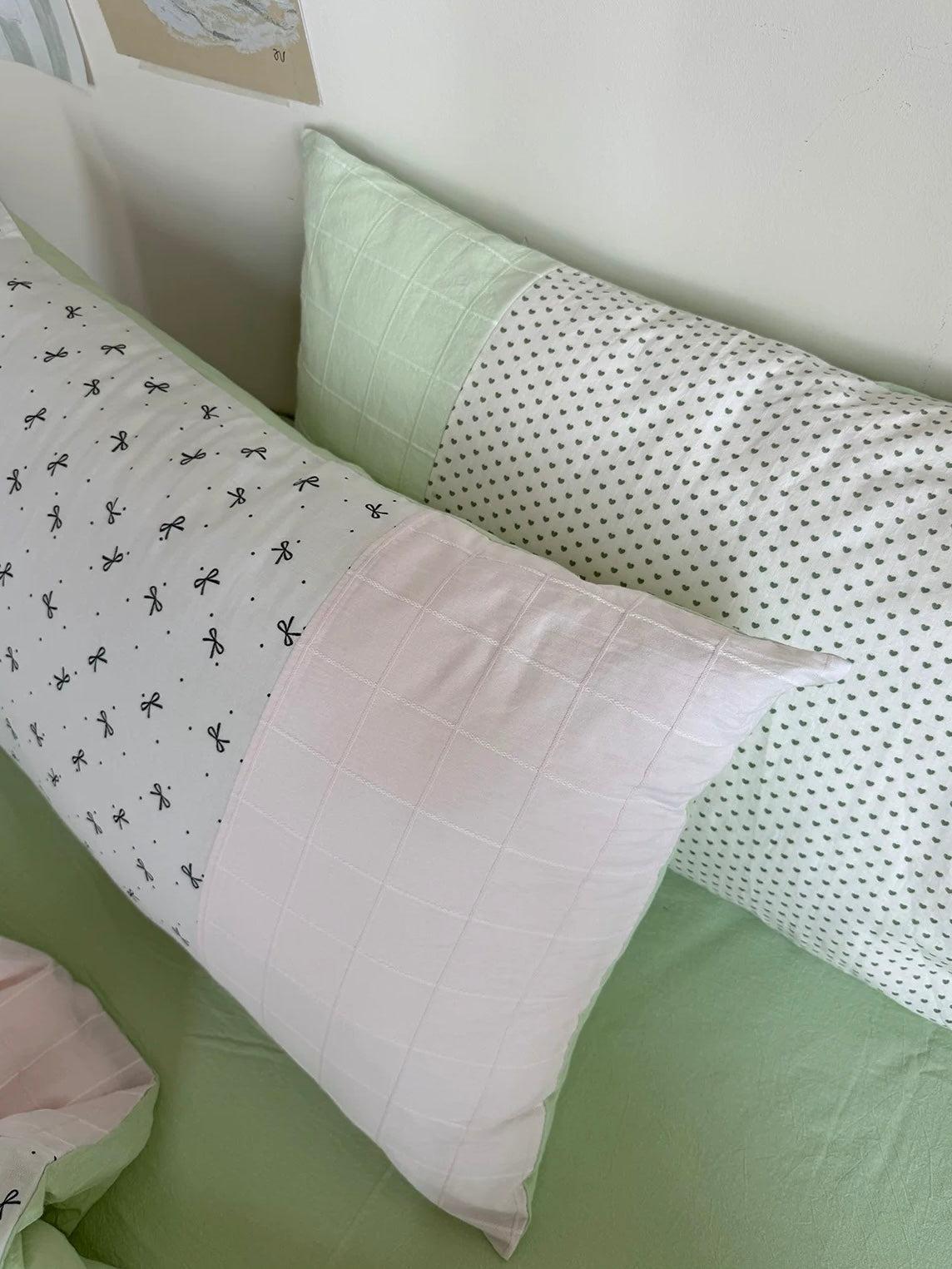 Pink panel and bow-print pillowcases against mint green bedding