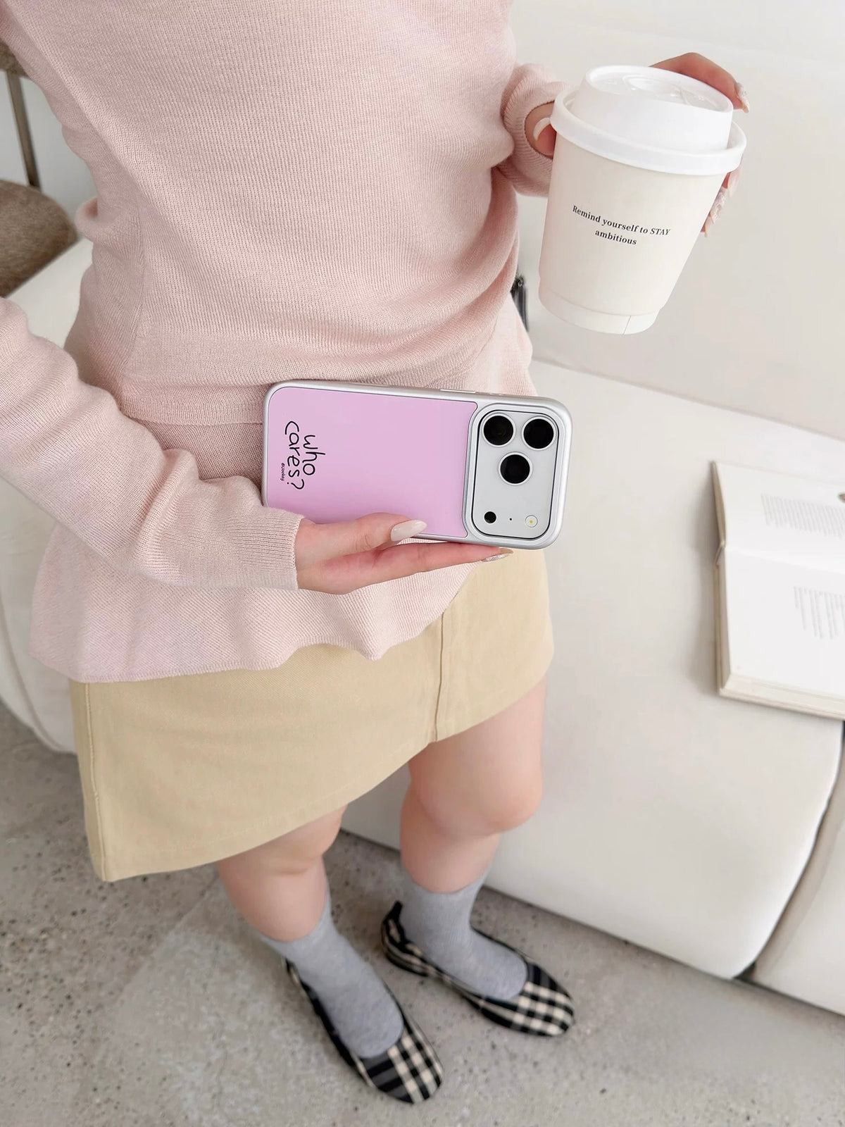 Pink phone case held horizontally, showing its pale back, black lettering and silver colored border.