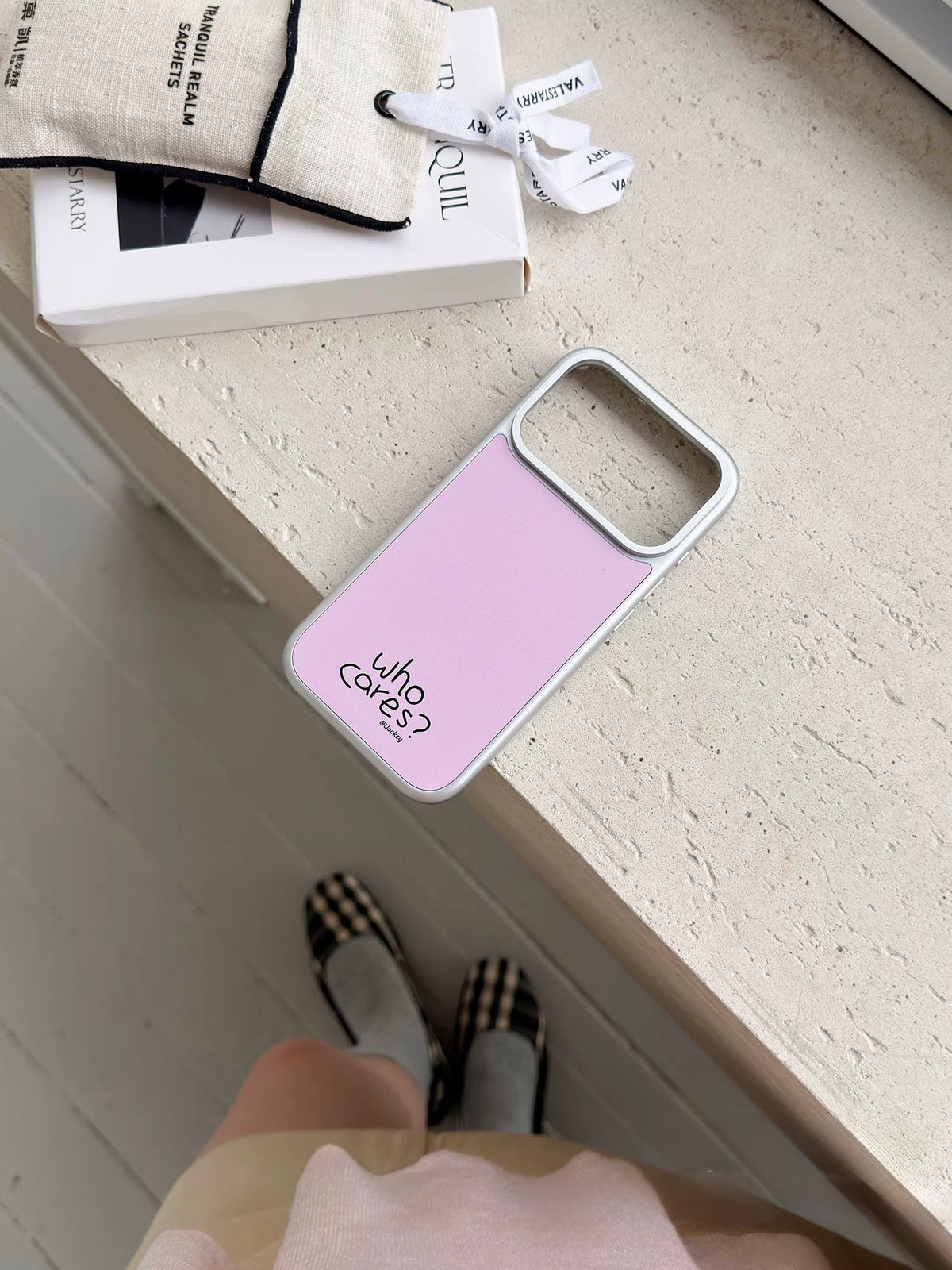 Pink phone case shown empty, with a wide camera opening, a silver colored border and black lettering.