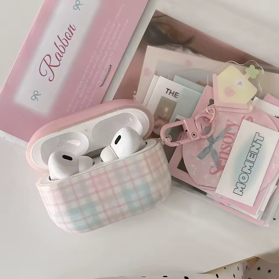 Wireless earbuds in a pink plaid case with a pink box in the background