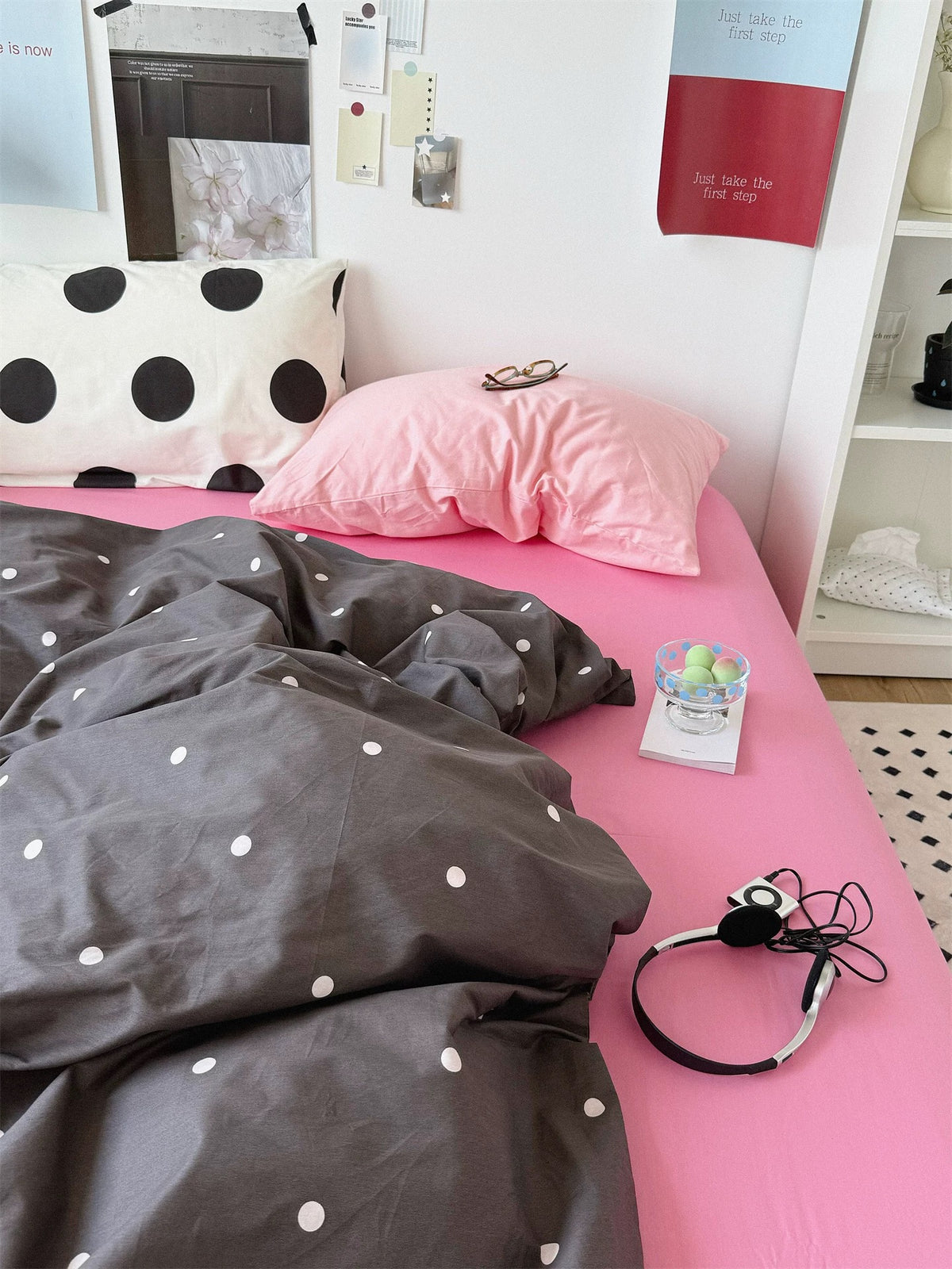 Pink polka dot bedding combines a large black dotted pillow with a solid baby pink pillow above the dark cover.