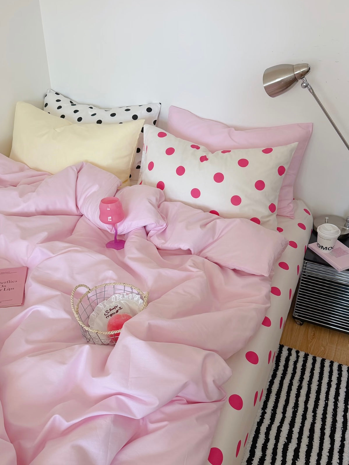 Pink polka dot bedding set with a plain pink cover, yellow and dotted pillows, and a white sheet with fuchsia dots.