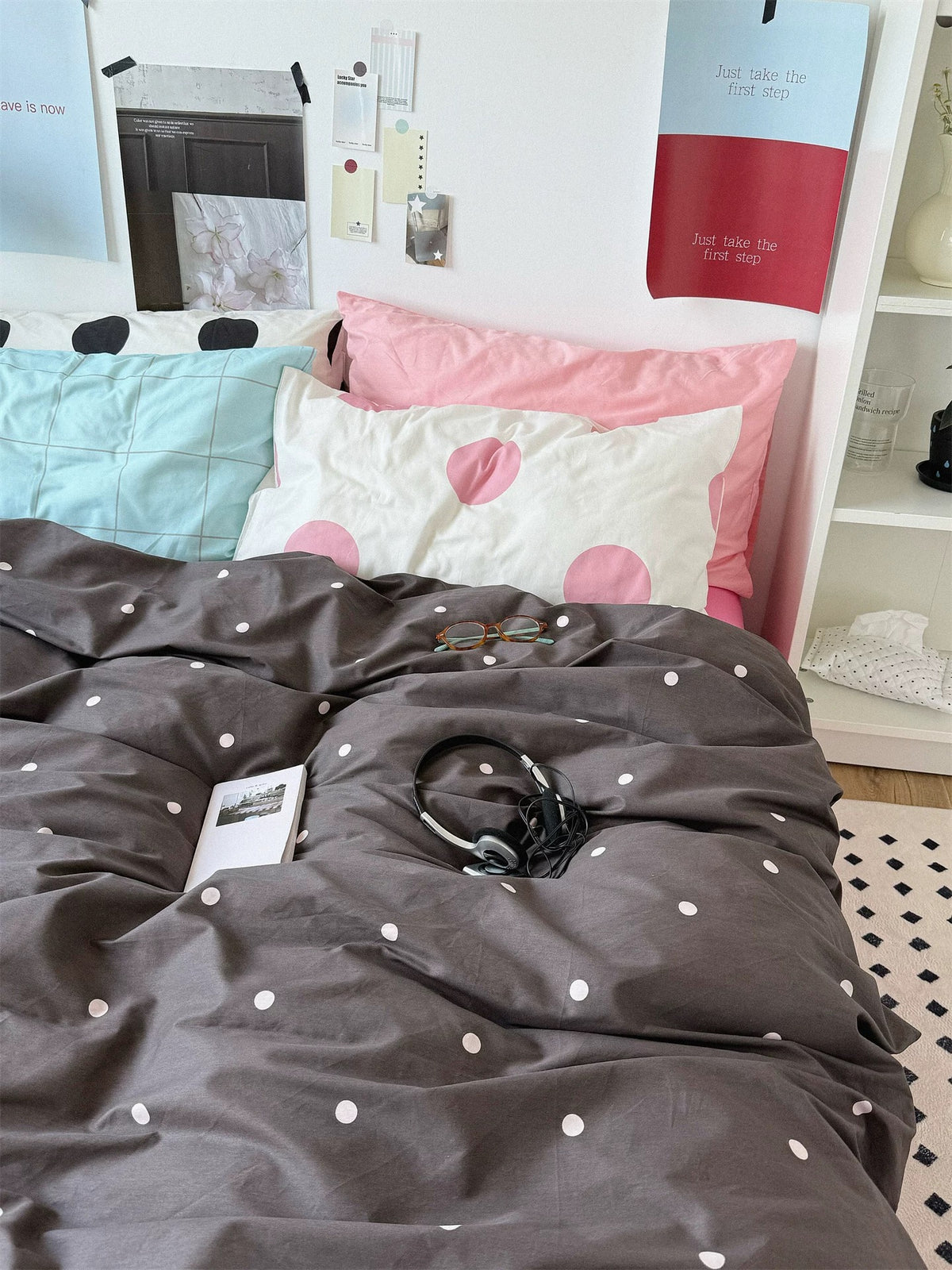 A wide front view of pink polka dot bedding shows a dark dotted cover and blue, pink and black pillow designs.