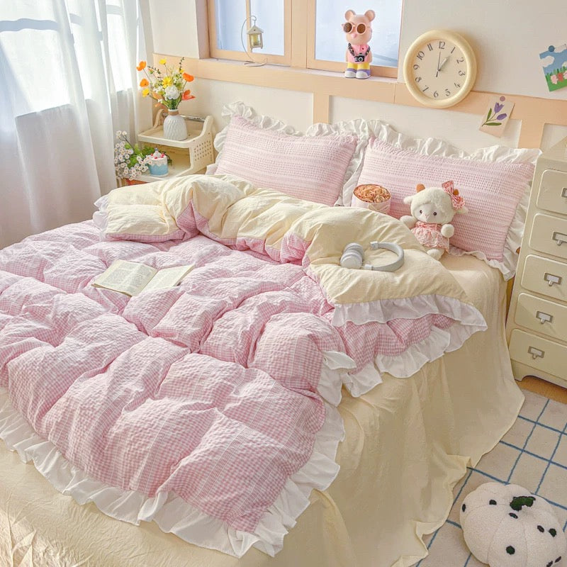 Pink and white bedding set with plush toys in a bedroom setting