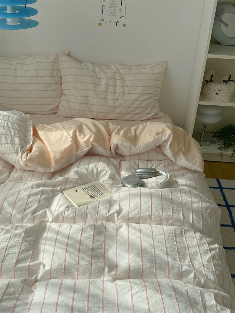 Bed with striped bedding and pillows, featuring a visible tag.