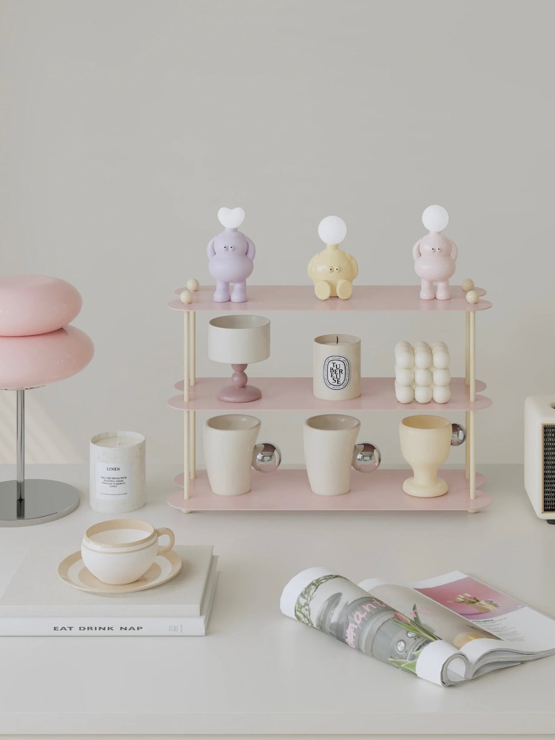 A blue mug display shelf with cream posts holds cups across three open levels, with candles on the top tier.