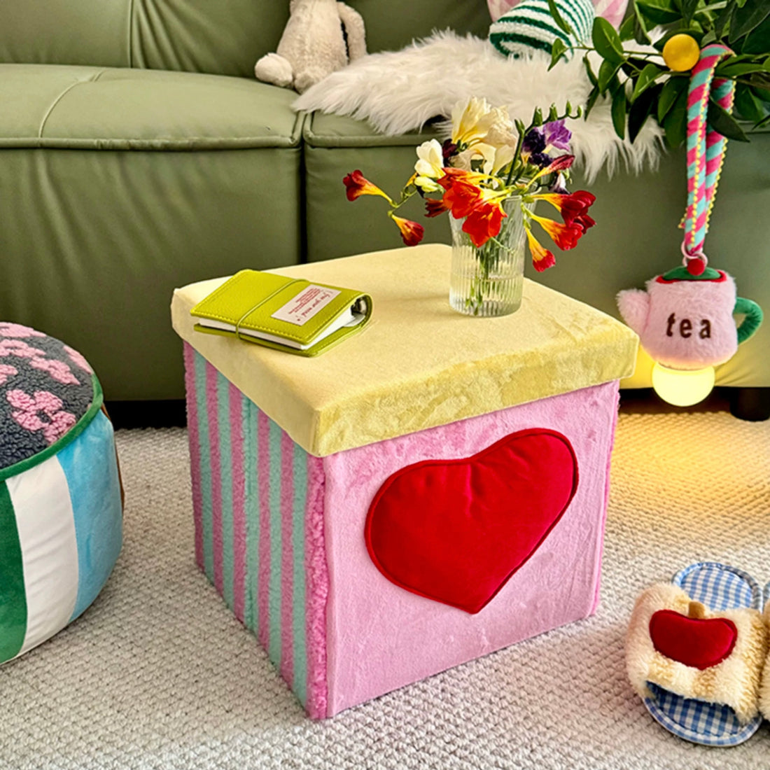 Green storage ottoman with heart detail styled beside a sofa