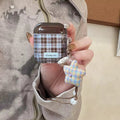 Plaid airpods case with a star-shaped charm held by a person.