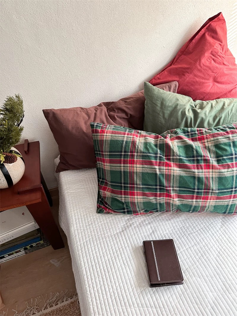 Green and red tartan pillowcases sit below upright red, green and chocolate brown designs.