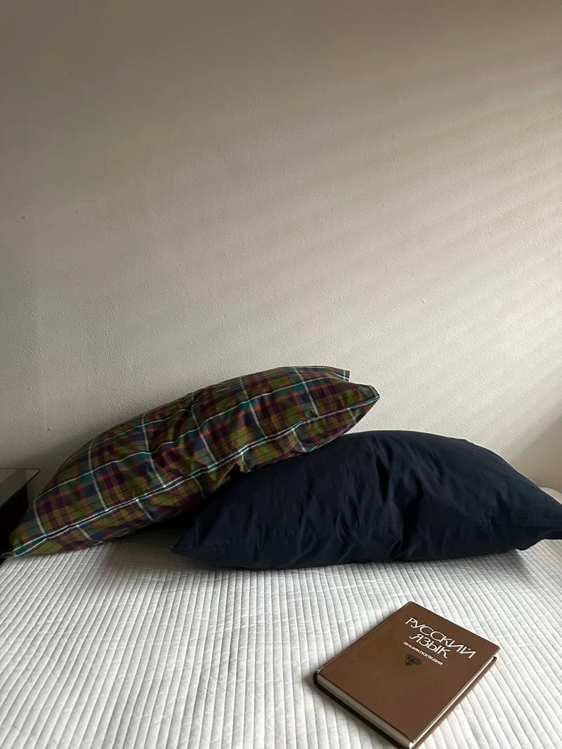 A plaid pillowcase placed diagonally over a navy blue pillowcase.