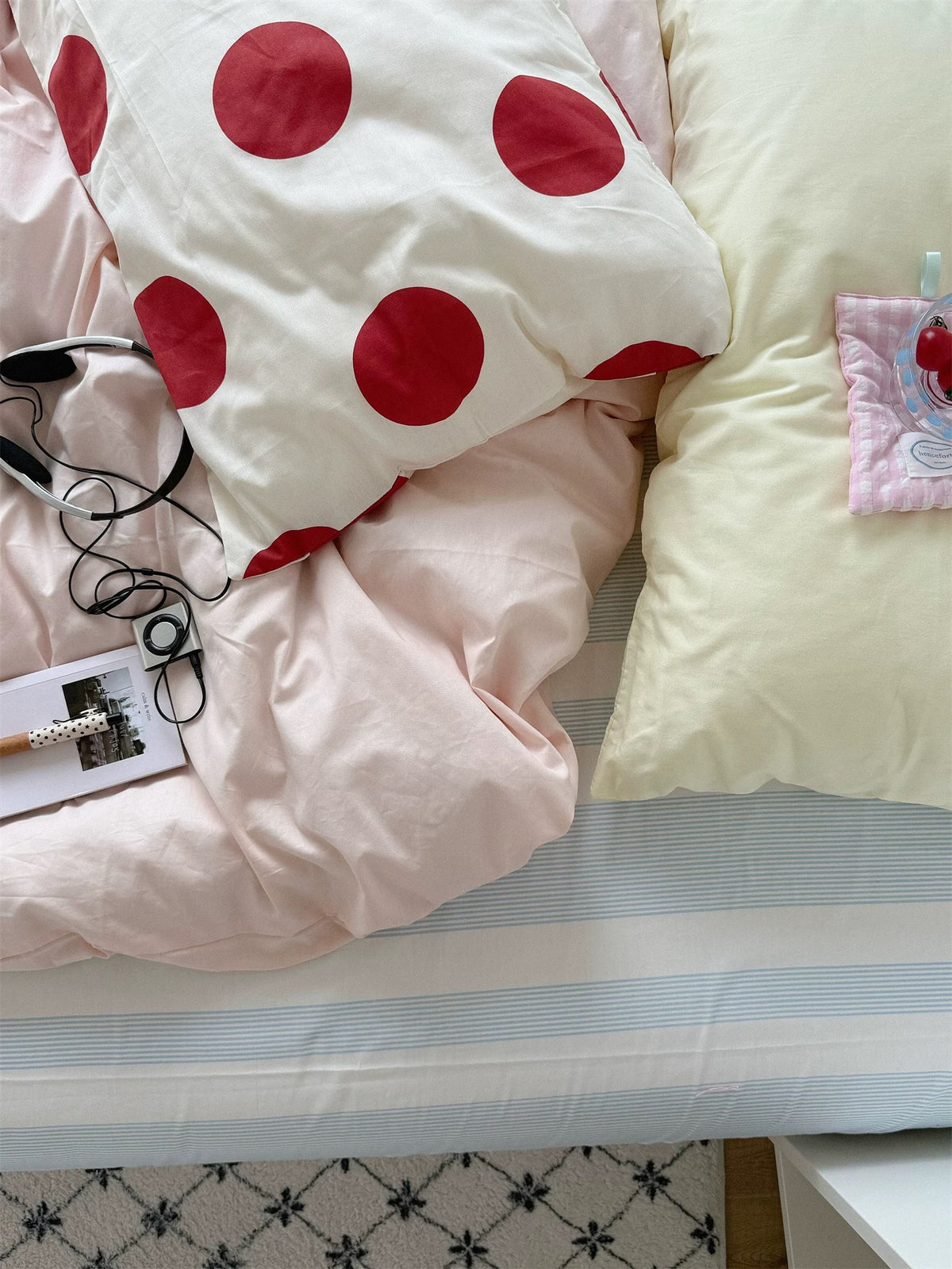 Overhead detail of a large red dot pillowcase, pale yellow pillow and pink duvet cover.