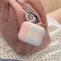 Pink textured pouch with a checkered air pod case hanging from a zipper.