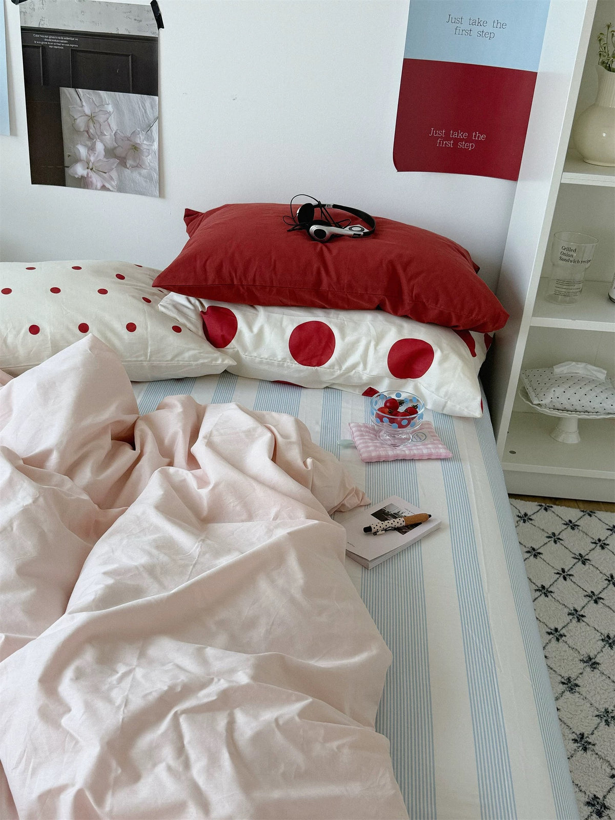 Preppy bedding pairs a red pillow with large red dots above a rumpled pink duvet cover.
