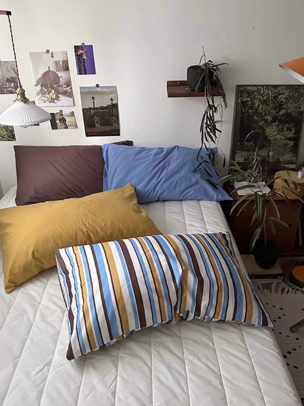 A Preppy pillowcase with colorful stripes sits in front of solid mustard, blue and mocha pillowcases.