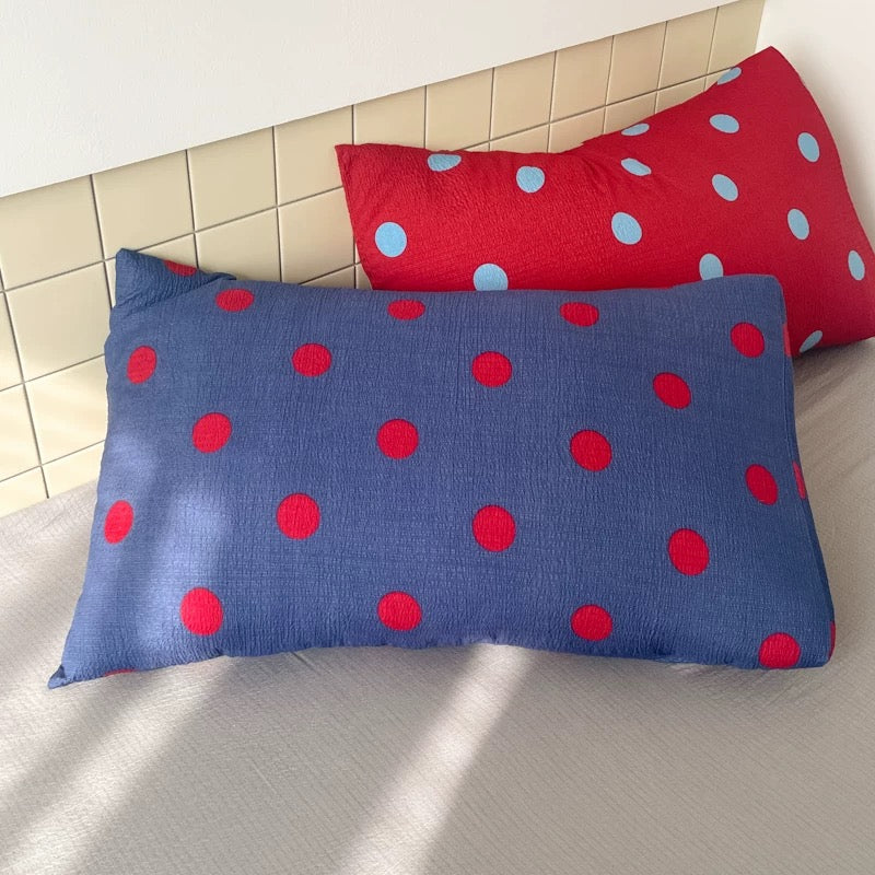 Blue polka dot duvet cover set with red dots laid flat to show fabric texture and print details clearly.