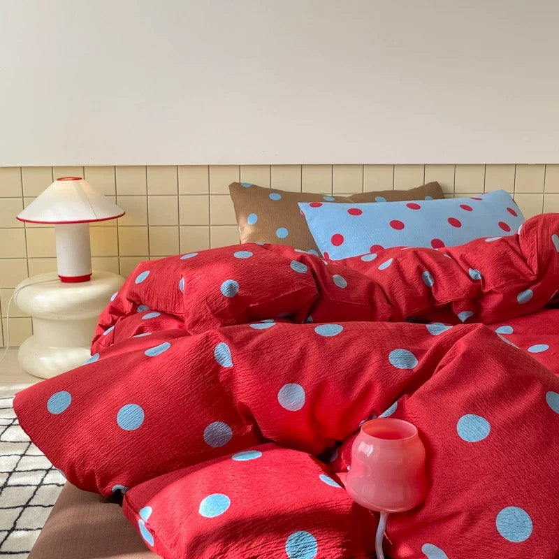 Preppy red and blue polka dot bedding displayed in bright college dorm room interior style