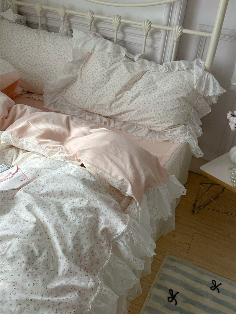 Bed with white and pink floral bedding in a bedroom setting