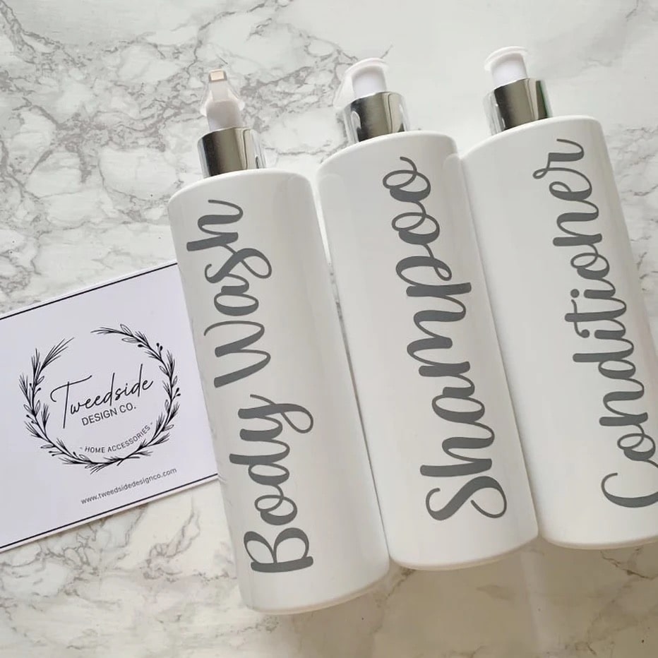 Reusable white pump bottles for shampoo, conditioner, and soap. Elegant farmhouse design for bathroom or hotel with eco-friendly bamboo pump heads.