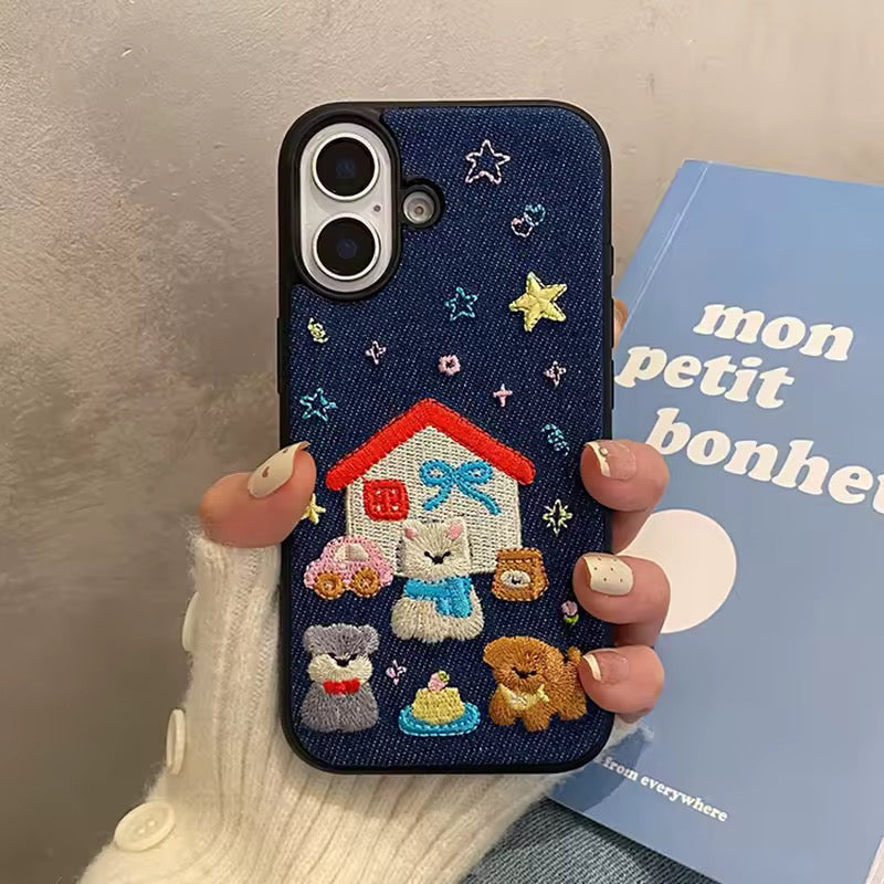 Phone case with embroidered design held by a person, with a book in the background.