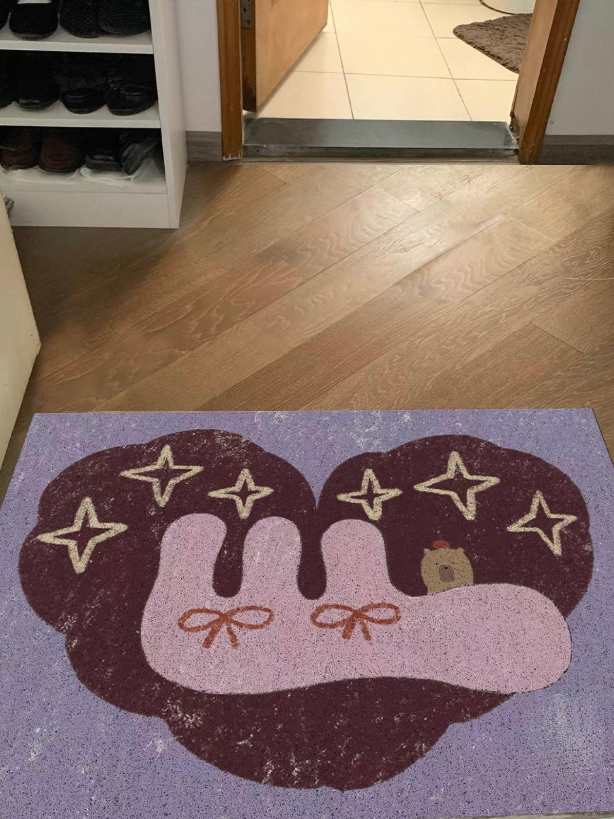 A purple capybara rug shows a dark rounded background behind pink bow details and pale yellow stars.