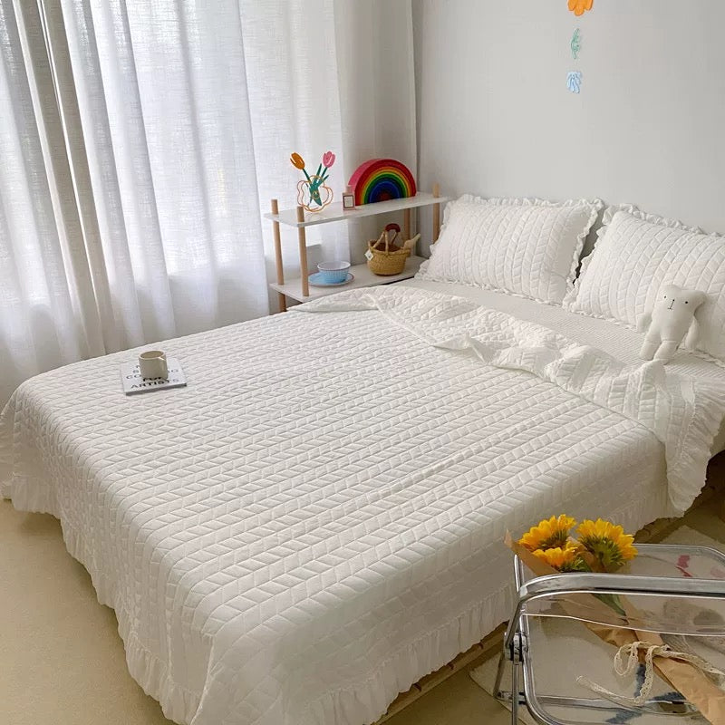 Quilted ruffle blanket with decorative edge and matching pillowcases