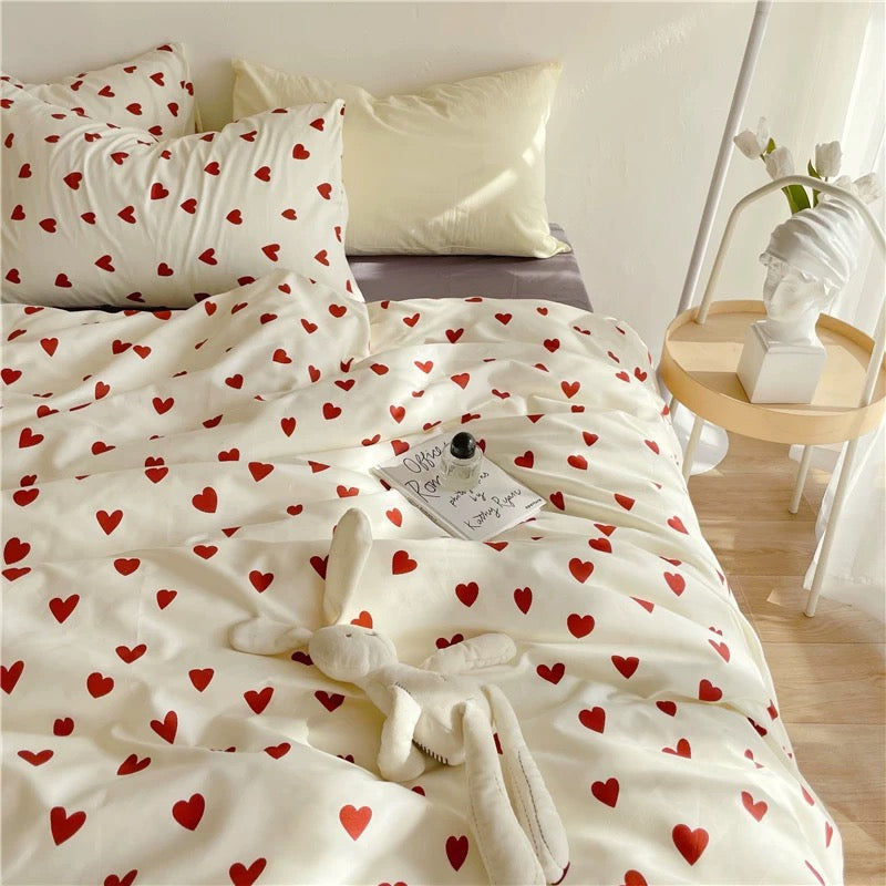 Red heart bedding set on a white bed with matching heart pillowcases and bedside decor
