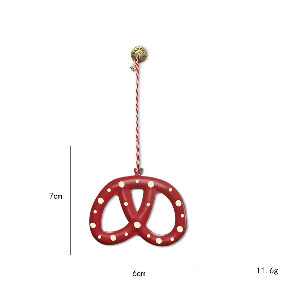 A red pretzel Christmas tree ornament has three open sections and white dots scattered across its face.