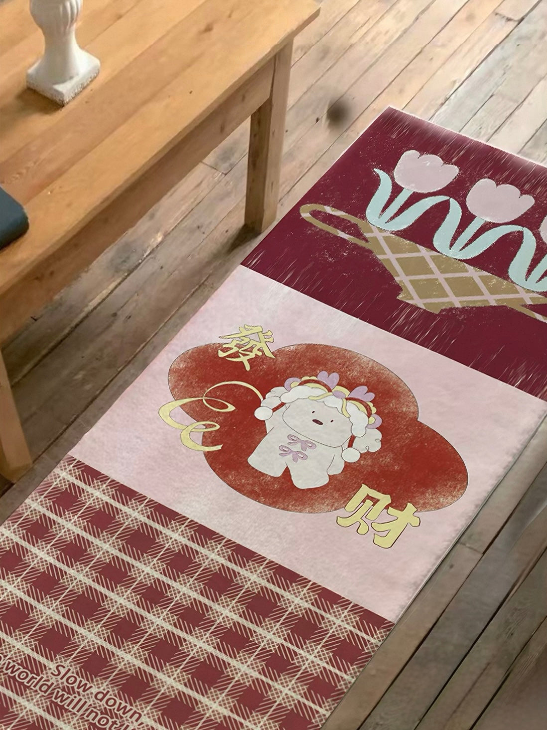 A red tulip rug lies along a floor edge, showing pale flowers, a central character and a plaid panel.