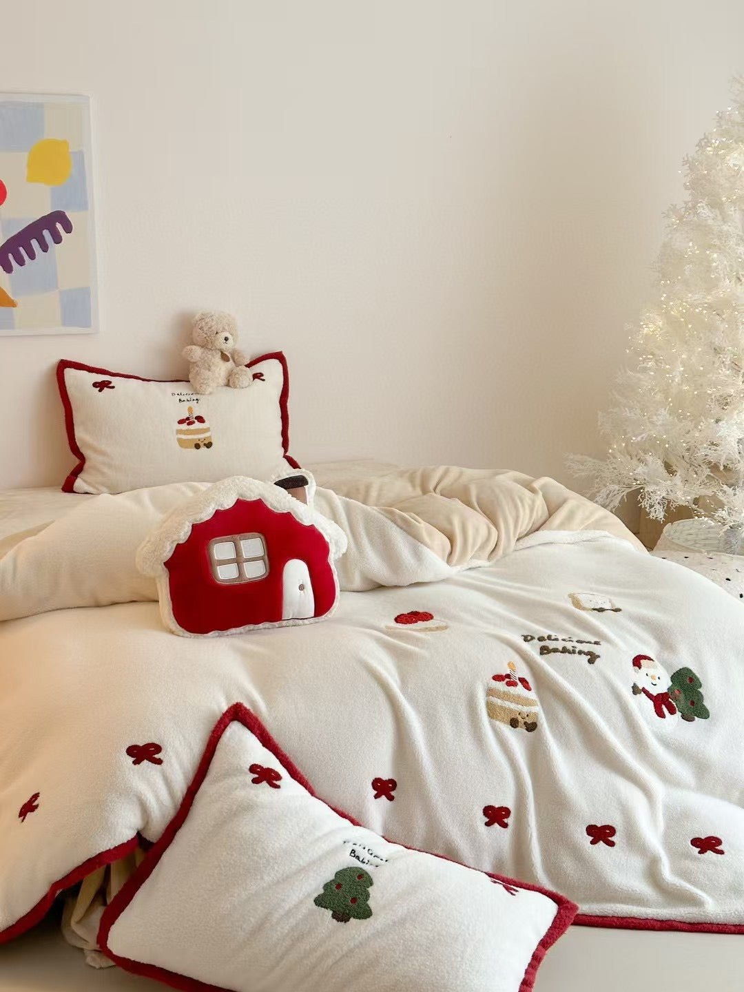 Red and white Christmas bedding styled with a red house-shaped cushion